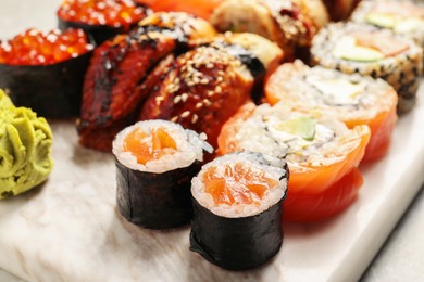 Photo of Different tasty sushi rolls on board, closeup