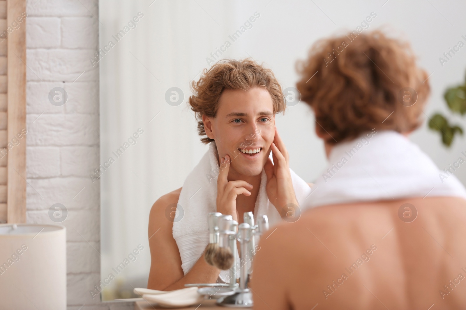 Photo of Young man looking in mirror after shaving at home