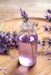 Photo of Glass bottle of natural cosmetic oil and lavender flowers on wooden plate