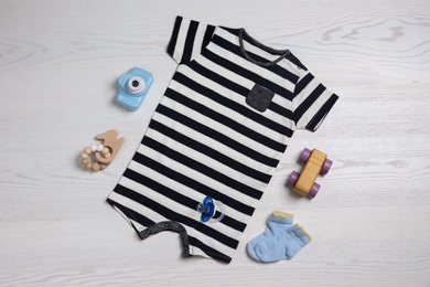 Flat lay composition with baby clothes and toys on white wooden table