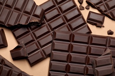 Photo of Pieces of delicious dark chocolate bars on beige background, flat lay