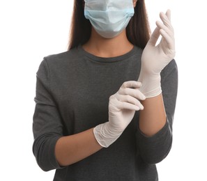 Woman in protective face mask putting on medical gloves against white background, closeup