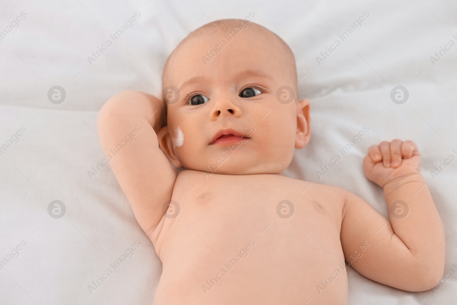 Photo of Cute little baby with cream on face on white blanket