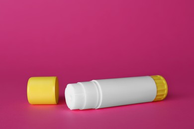 Photo of Blank glue stick and cap on fuchsia background, space for text
