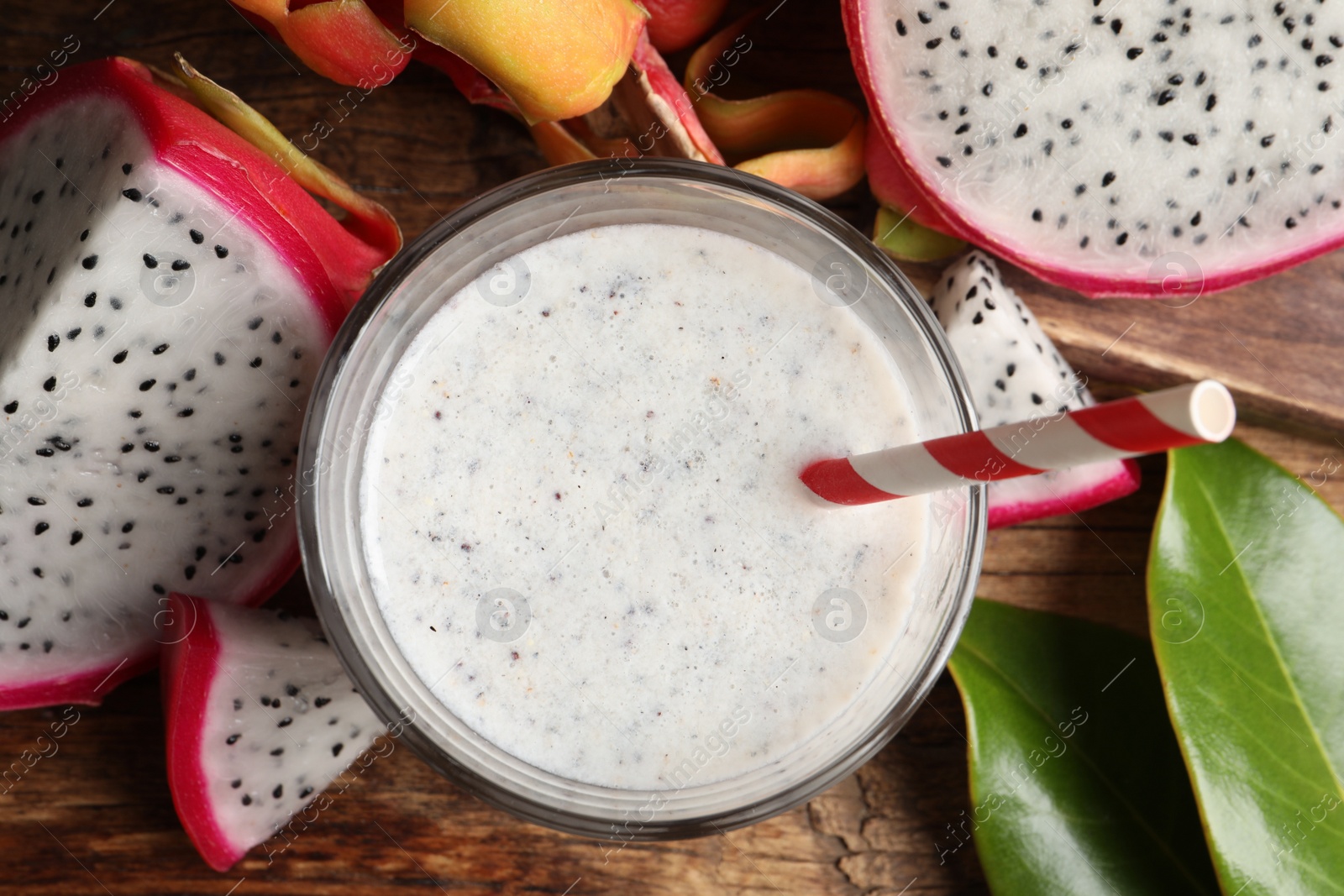 Photo of Delicious pitahaya smoothie and fresh fruits on wooden table, flat lay