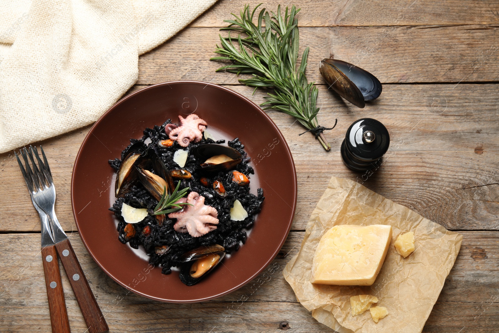 Photo of Delicious black risotto with seafood served on wooden table, flat lay