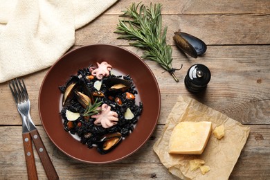 Delicious black risotto with seafood served on wooden table, flat lay