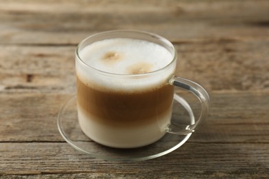 Aromatic coffee in glass cup on wooden table, closeup