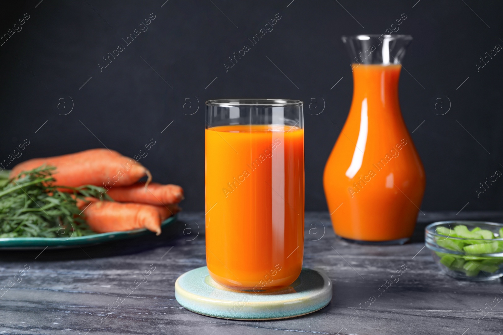 Photo of Tasty refreshing carrot juice on black marble table