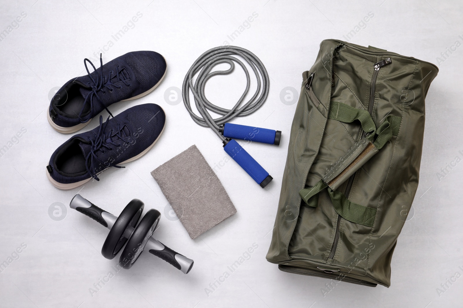 Photo of Gym bag and sports equipment on white background, flat lay