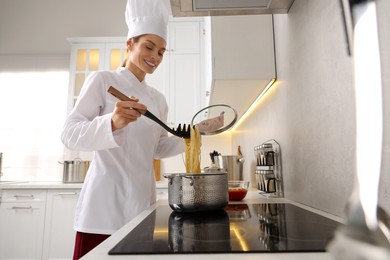Photo of Professional chef cooking delicious pasta in saucepan indoors