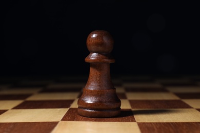 Photo of Alone pawn on chess desk against dark background. Victory concept