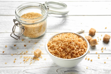 Jar and bowl with brown sugar on wooden table