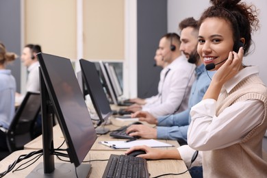 Photo of African American call center operator with headset and her colleagues working in modern office