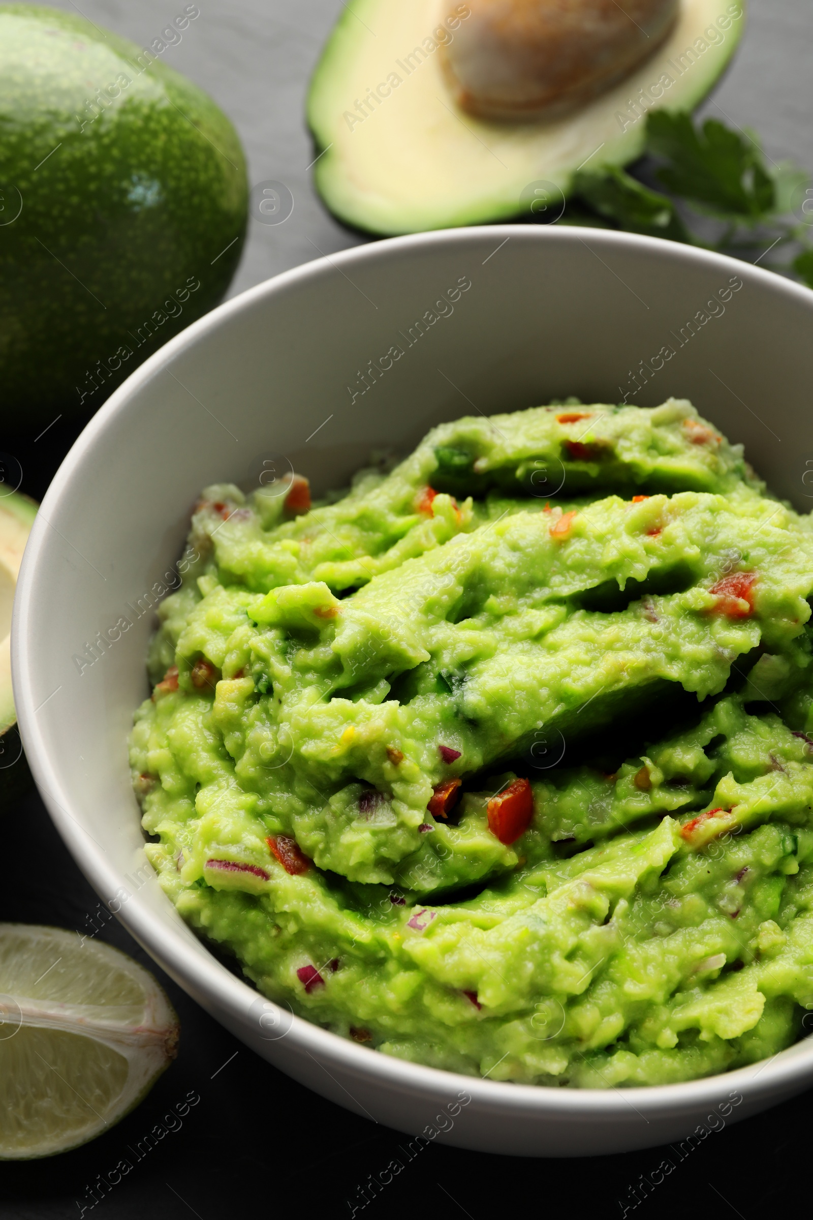 Photo of Delicious guacamole, fresh avocado and parsley on grey table