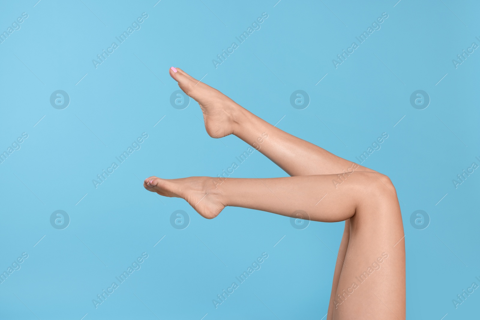 Photo of Woman with beautiful long legs on light blue background, closeup