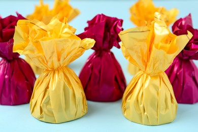 Candies in colorful wrappers on light blue background, closeup