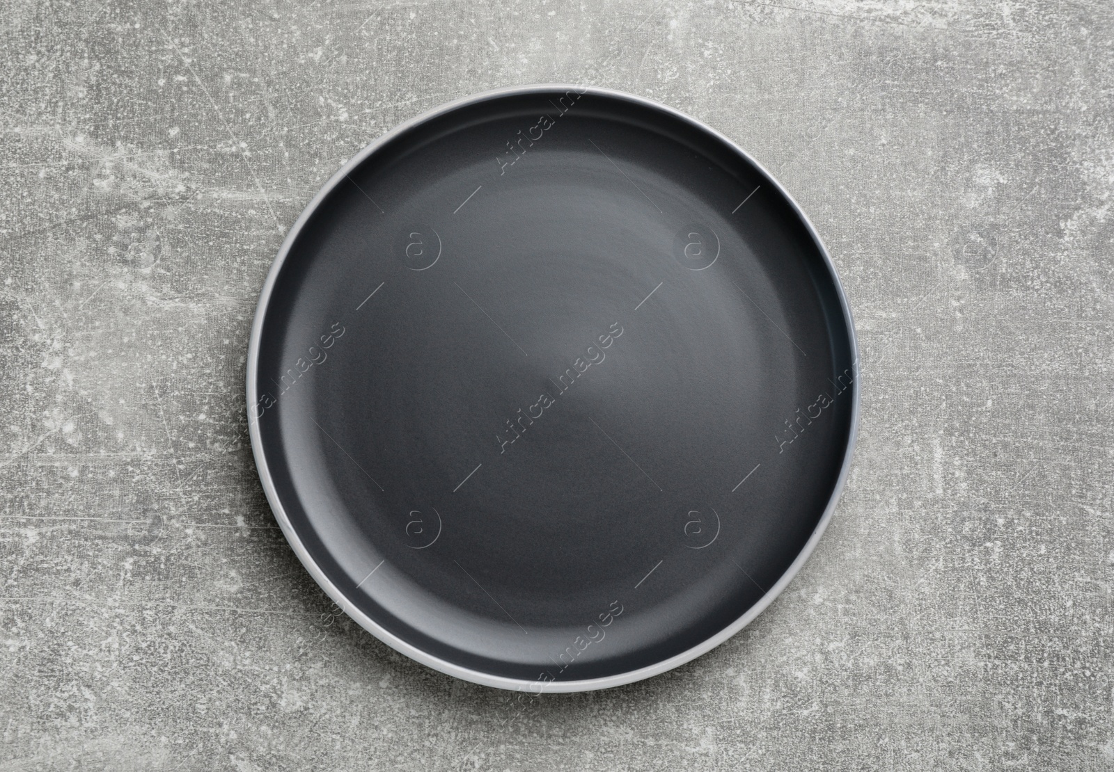 Photo of New dark plate on light grey table, top view