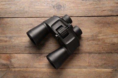 Photo of Modern binoculars on wooden table, top view