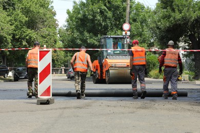 Photo of MYKOLAIV, UKRAINE - AUGUST 04, 2021: Workers with road repair machinery laying new asphalt