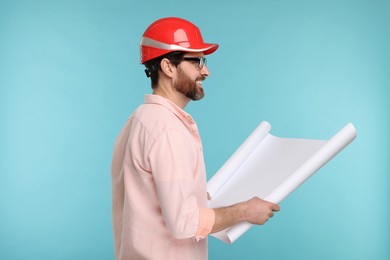 Photo of Architect in hard hat with draft on light blue background