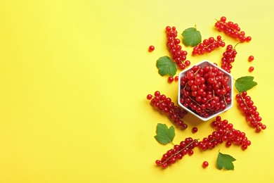 Photo of Delicious red currants and leaves on yellow background, flat lay. Space for text