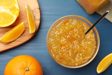 Delicious orange marmalade and fruit slices on blue wooden table, flat lay