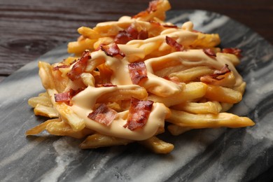 Photo of Delicious French fries with bacon and cheese sauce on table, closeup