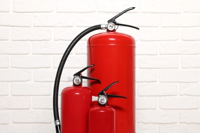 Photo of Red fire extinguishers near white brick wall