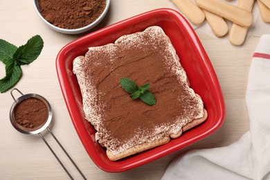 Red bowl with delicious tiramisu cake on white wooden table, flat lay