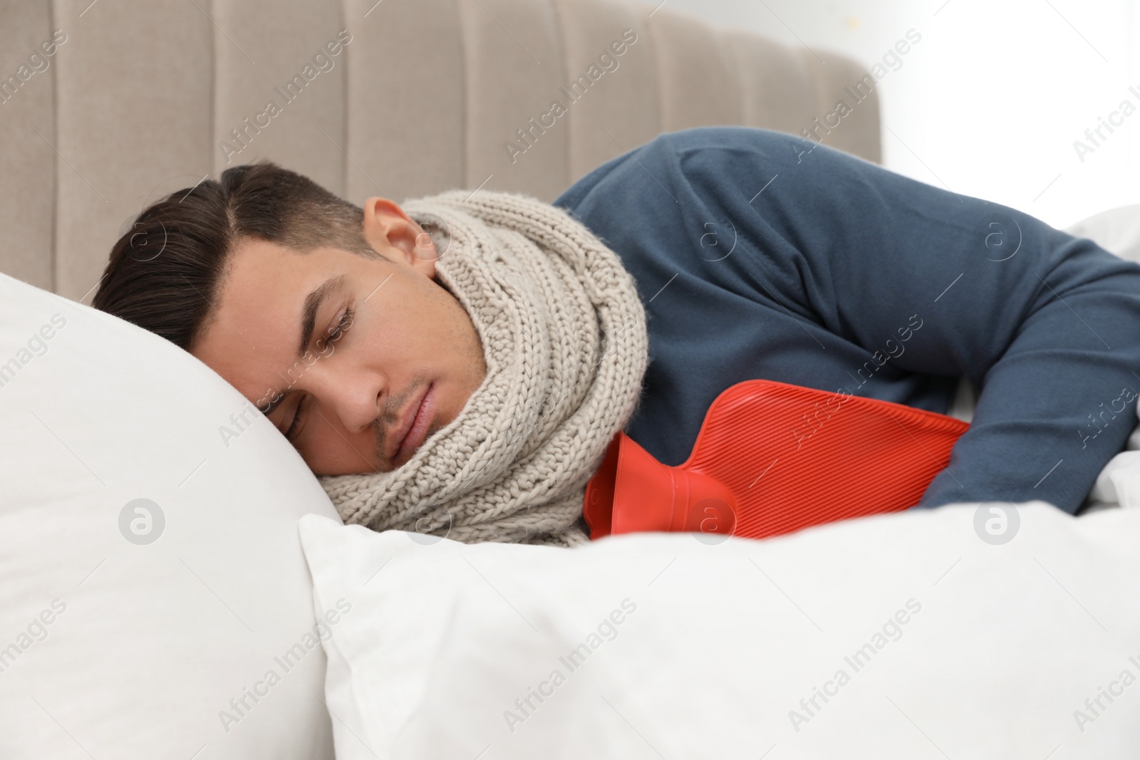 Photo of Ill man with hot water bottle sleeping at home