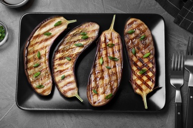 Photo of Delicious grilled eggplant halves served on grey table, flat lay