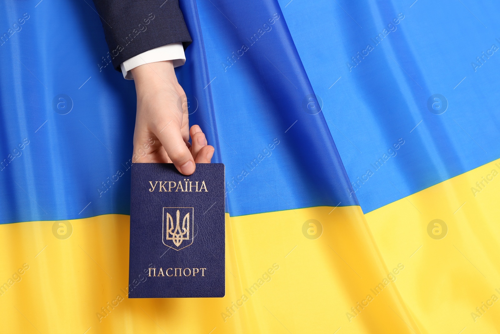 Photo of Woman holding Ukrainian internal passport over national flag, top view. Space for text
