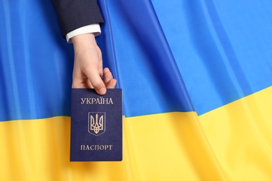 Woman holding Ukrainian internal passport over national flag, top view. Space for text