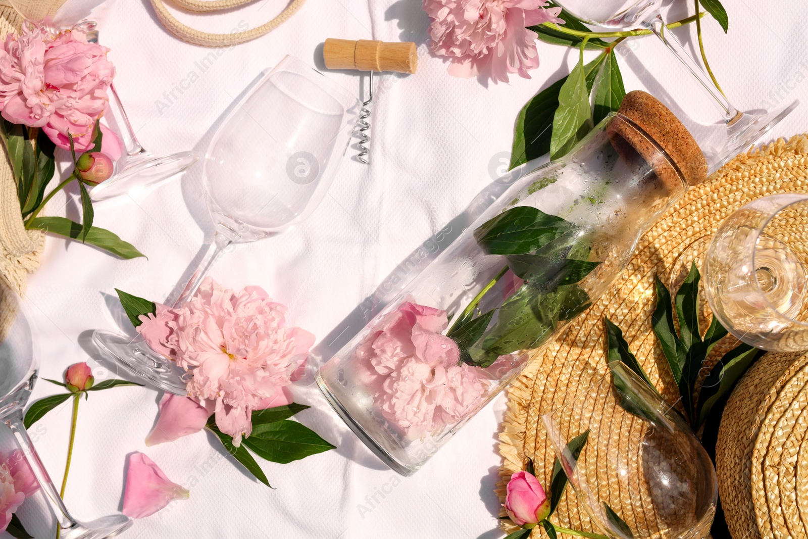 Photo of Flat lay composition with beautiful peonies and wineglasses on white fabric