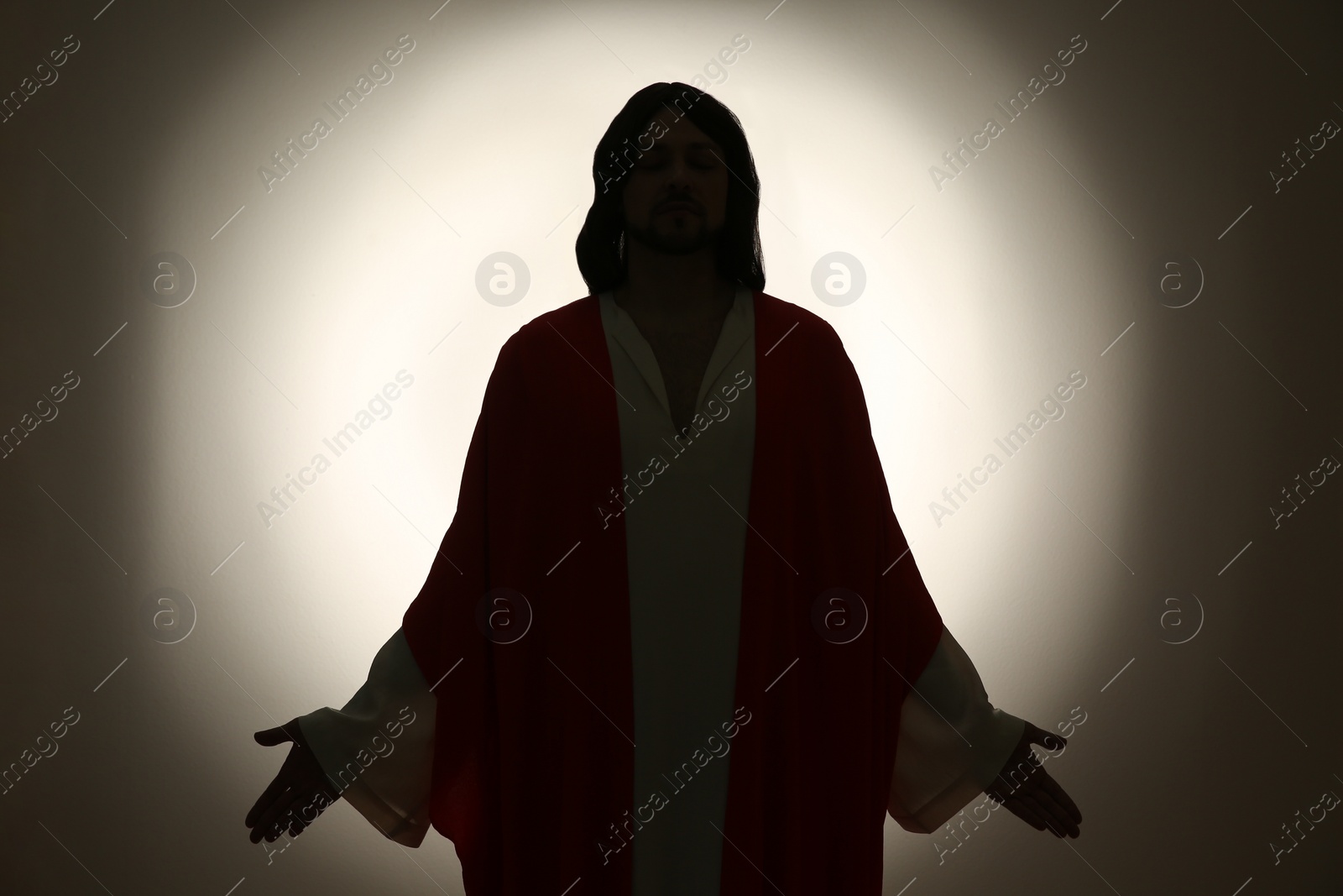 Photo of Silhouette of Jesus Christ with outstretched arms on color background