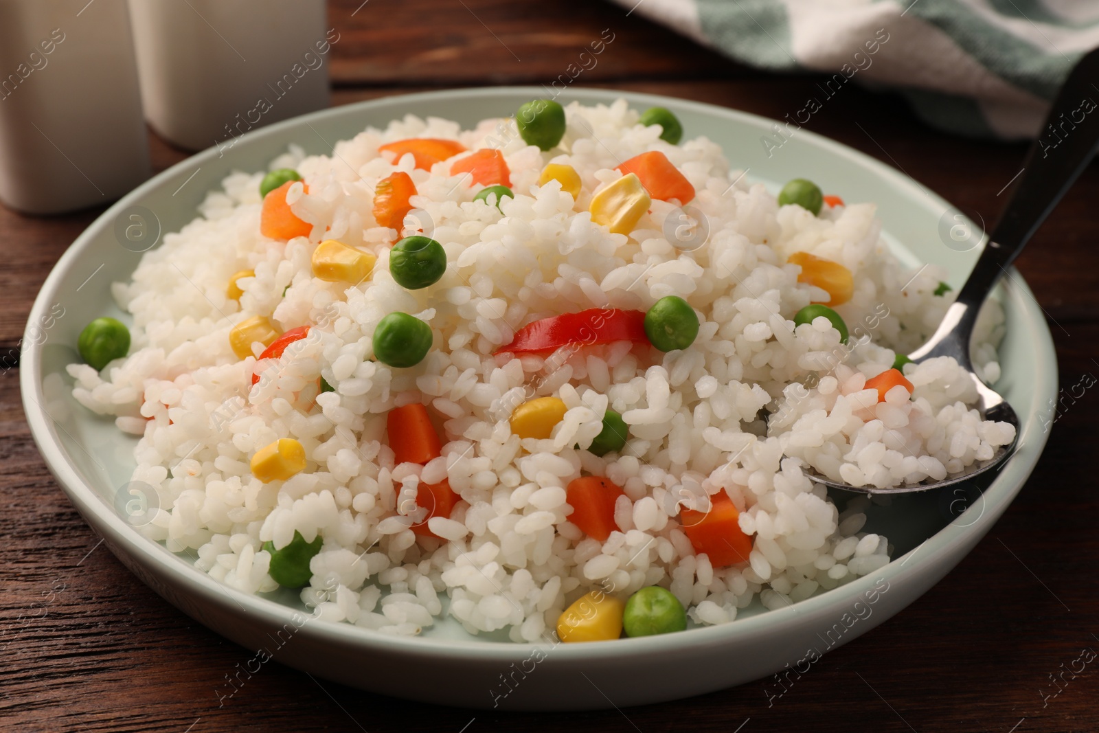 Photo of Delicious rice with vegetables served on wooden table, closeup