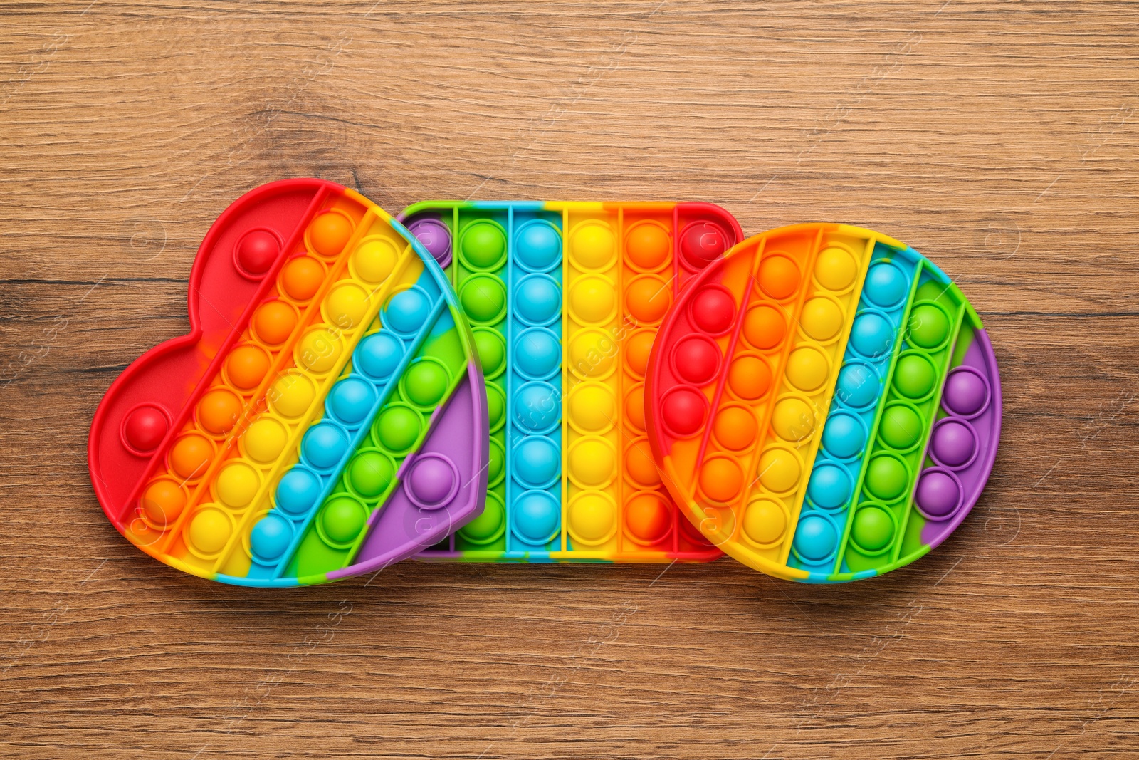 Photo of Rainbow pop it fidget toys on wooden table, flat lay