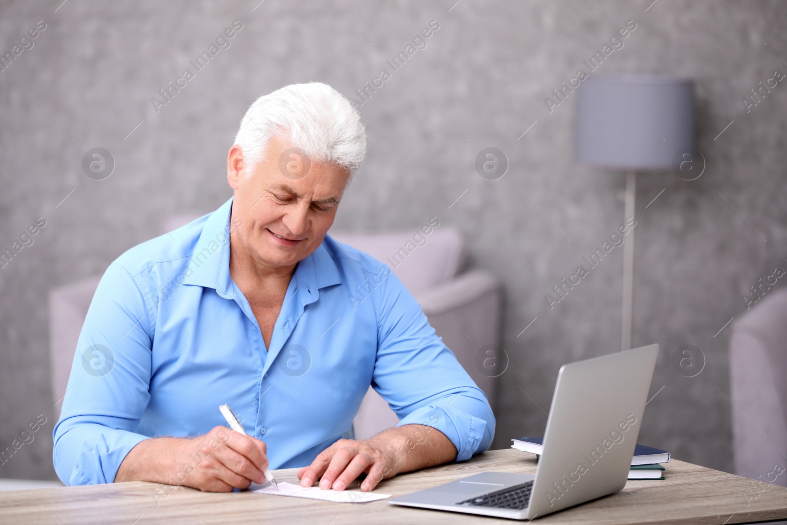 Photo of Portrait of senior man filling out lottery ticket at table