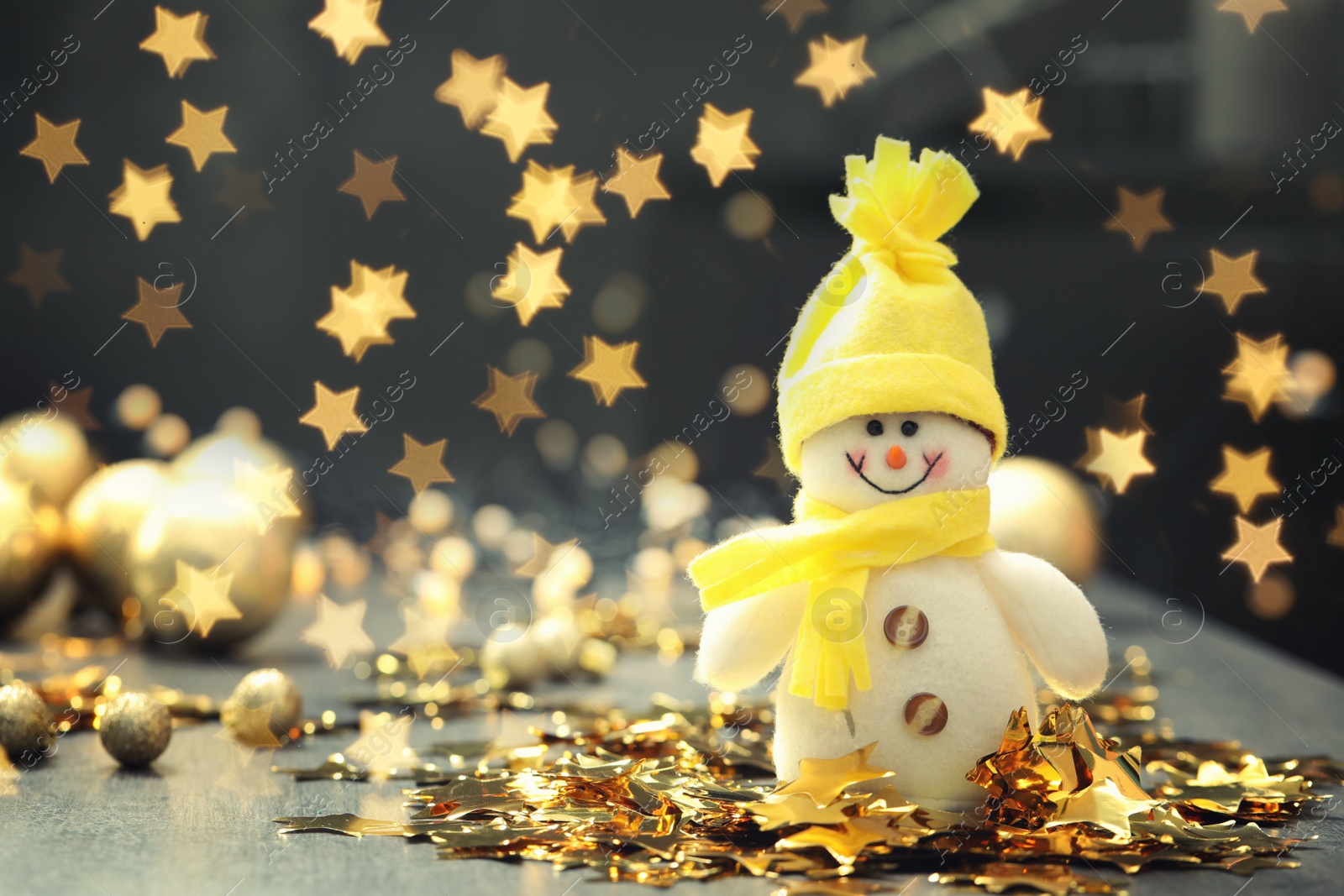 Image of Cute snowman and Christmas decor on table, bokeh effect