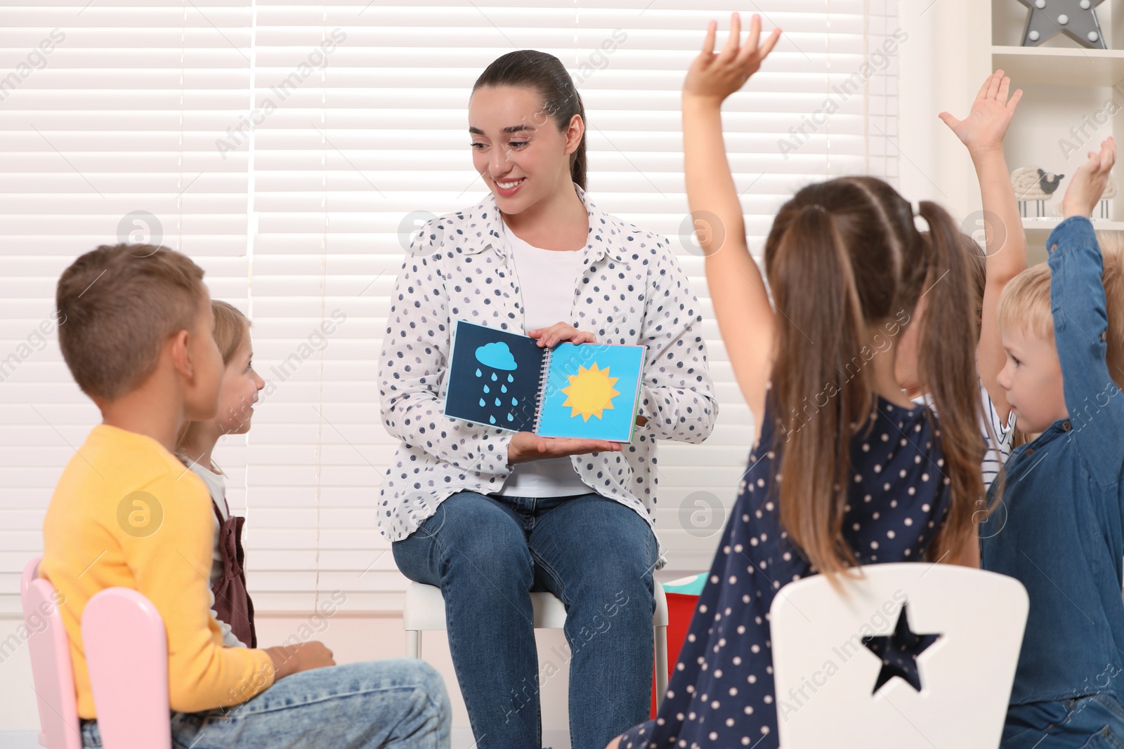 Photo of Nursery teacher and group of cute little children studying with fun in kindergarten. Playtime activities