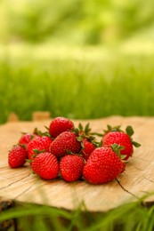 Photo of Pile of delicious ripe strawberries on tree stump outdoors. Space for text