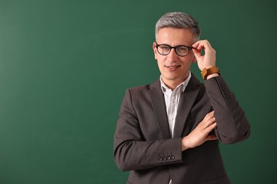 Teacher in glasses near chalkboard, space for text