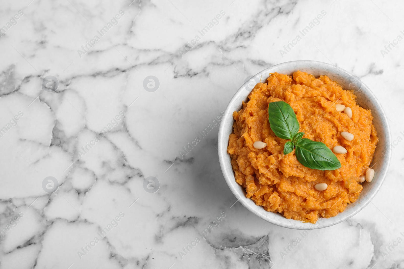 Photo of Bowl of tasty sweet potato puree on marble table, top view. Space for text