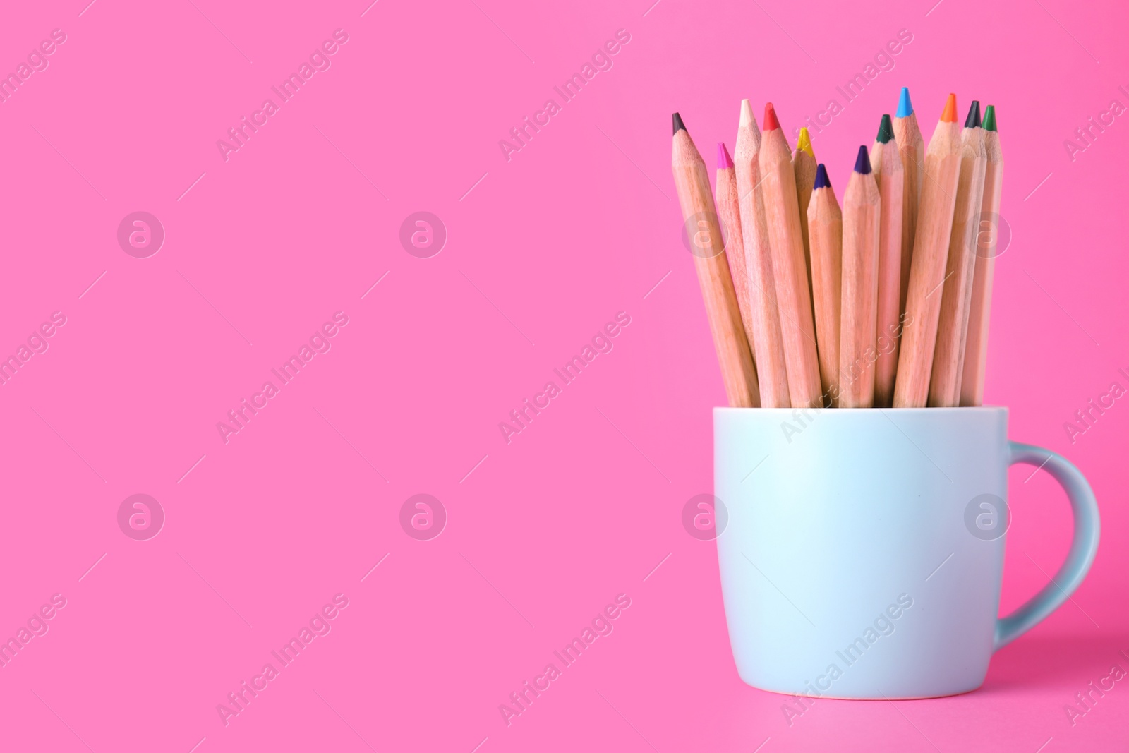 Photo of Colorful pencils in cup on pink background. Space for text