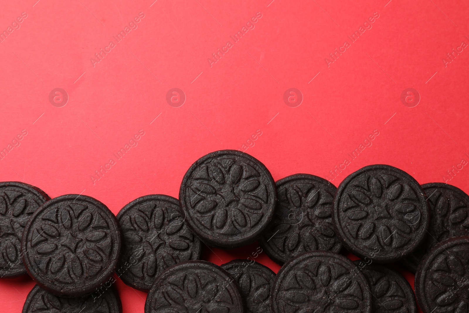 Photo of Tasty sweet sandwich cookies on red background, flat lay. Space for text