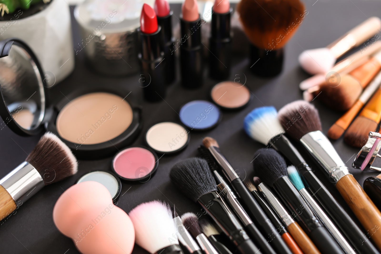 Photo of Different makeup brushes and cosmetic products on black background