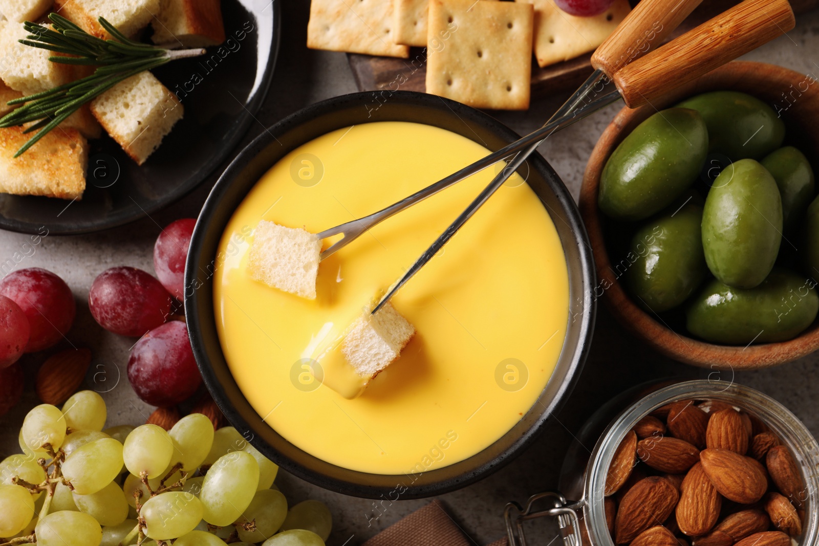 Photo of Tasty cheese fondue and snacks on grey table, flat lay