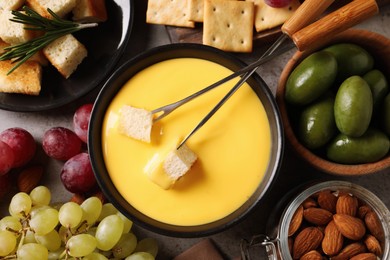 Tasty cheese fondue and snacks on grey table, flat lay