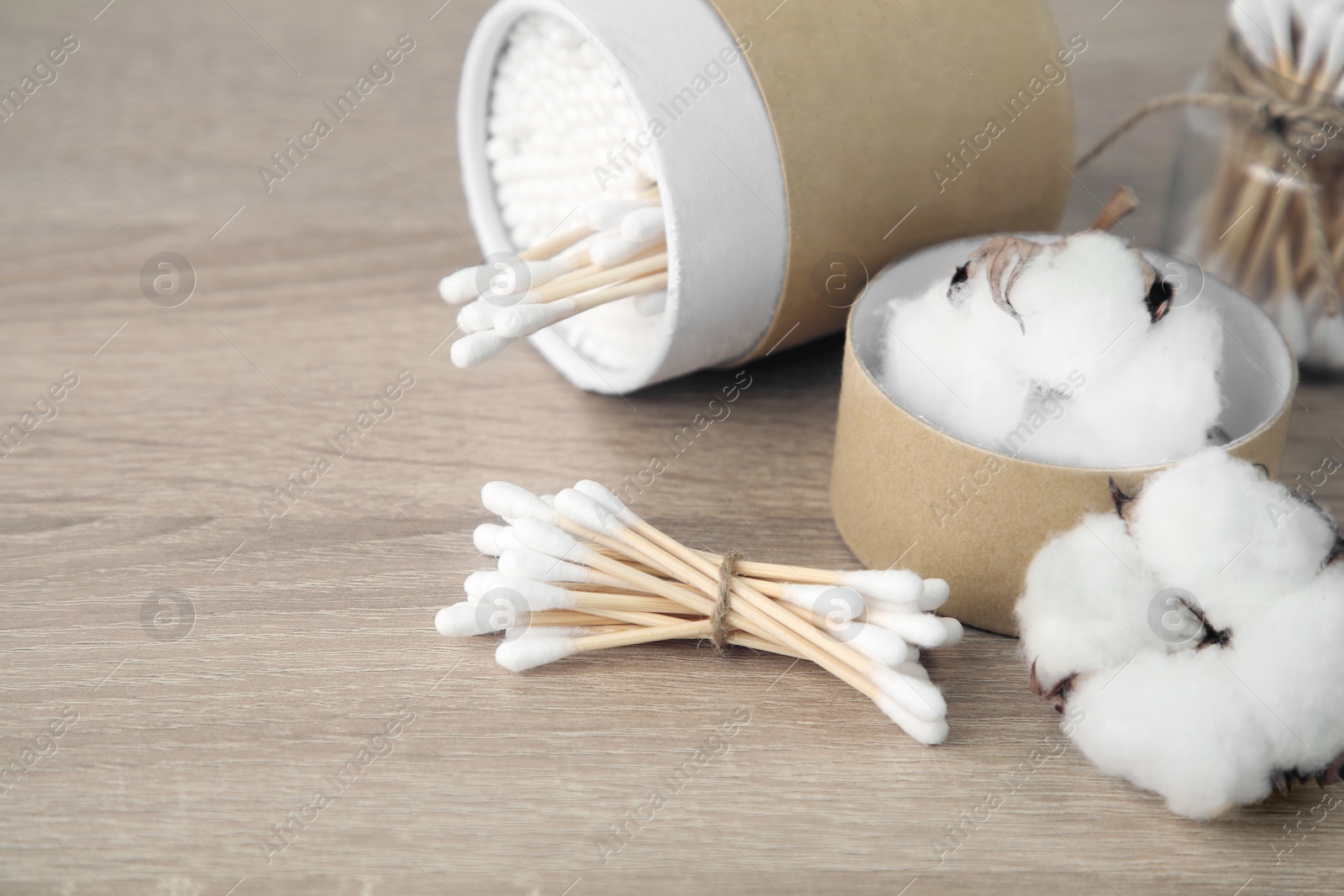 Photo of Cotton swabs and flowers on wooden table. Space for text